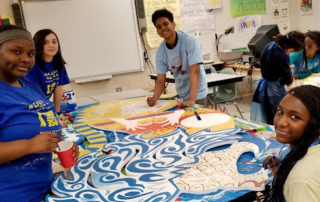 Students around an animodule on a table being painted