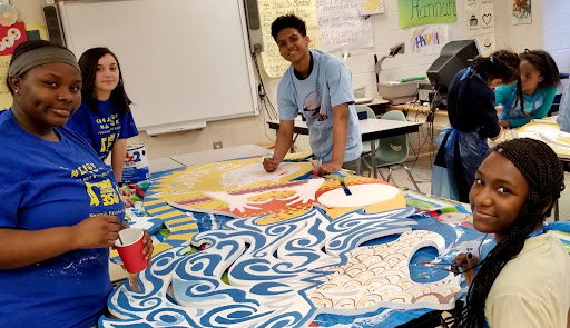 Students around an animodule on a table being painted